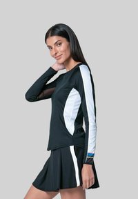 Zwarte sportieve top met lange mouwen en witte zijpanelen, gecombineerd met een zwarte plissé rok. Gladde textuur, aansluitend ontwerp, minimale accenten.