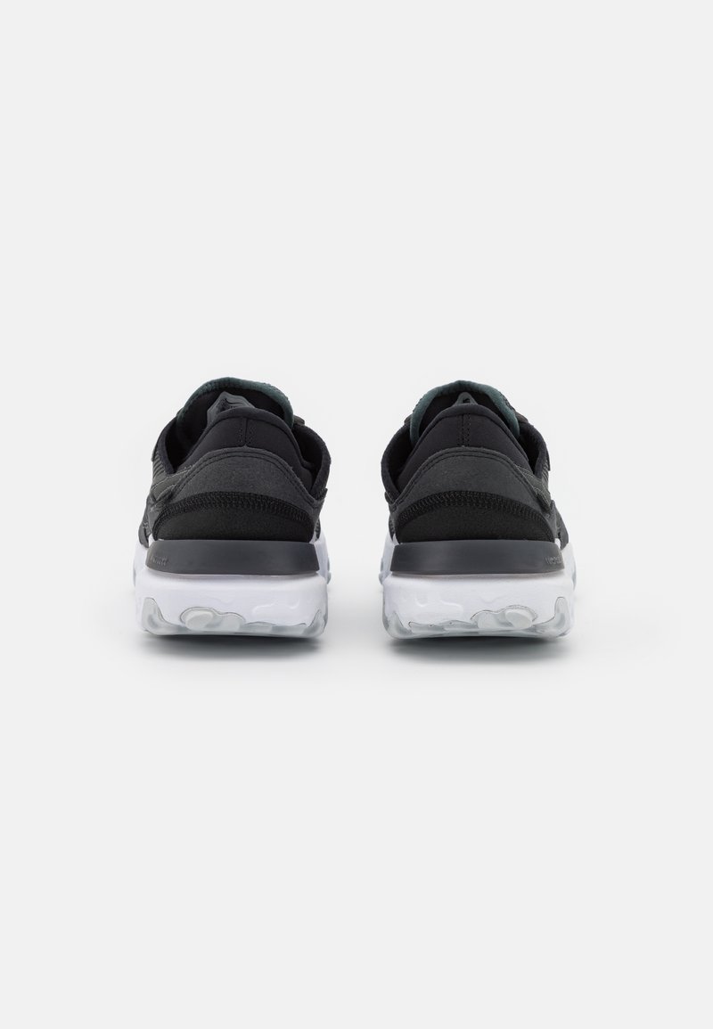 Zapatos deportivos negros con una parte superior texturizada, una suela blanca acolchada y un acento verde en contraste en el talón. Diseño de parte trasera redondeada.