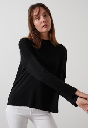 Black pullover sweater made of soft fabric, featuring a round neck, long sleeves, and a relaxed fit. Accents include side slits and ribbed cuffs.