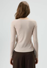 Lichtroze geribbelde top met lange mouwen en een boothals, met een getailleerd silhouet en een licht gebogen zoom. Gestructureerde stof met een subtiele glans.