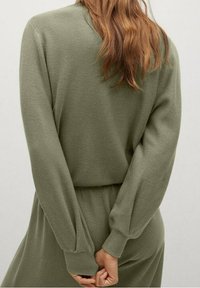 Olijfgroen gebreid sweater met lange mouwen, geribbelde textuur en een relaxte pasvorm. De achterkant is eenvoudig met een ronde halslijn en elastische tailleband.