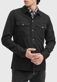 Schwarze Hemdjacke aus Baumwolltwill, mit zwei Brusttaschen, Knopfverschluss und Kragen. Glatte Textur und lockere Passform.
