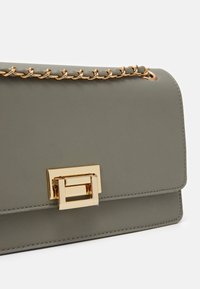 Szara skórzana torebka z metalowym złotym łańcuszkiem na ramię oraz prostokątnym złotym zapięciem. Gładka tekstura z precyzyjnym przeszyciem.