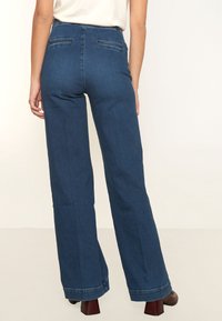 Kapelevat farkut tummansinisessä värissä, joissa on korkea vyötärö, kaksi takataskua ja siisti helman viimeistely. Suora pinta, jossa on hieman joustoa.