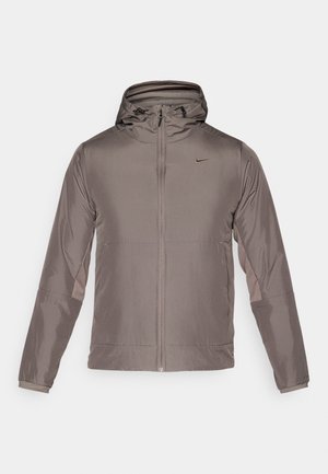 Kurtka Nike, lekka, szaro-brązowa, z kapturem, z pełnym zamkiem, długimi rękawami, kontrastowymi panelami i małym logo na piersi.