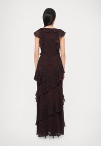 Maxi ruha fodros ujjal és réteges kialakítással. Fekete anyag mélyvörös paisley mintával és áramló, texturált sziluettel.