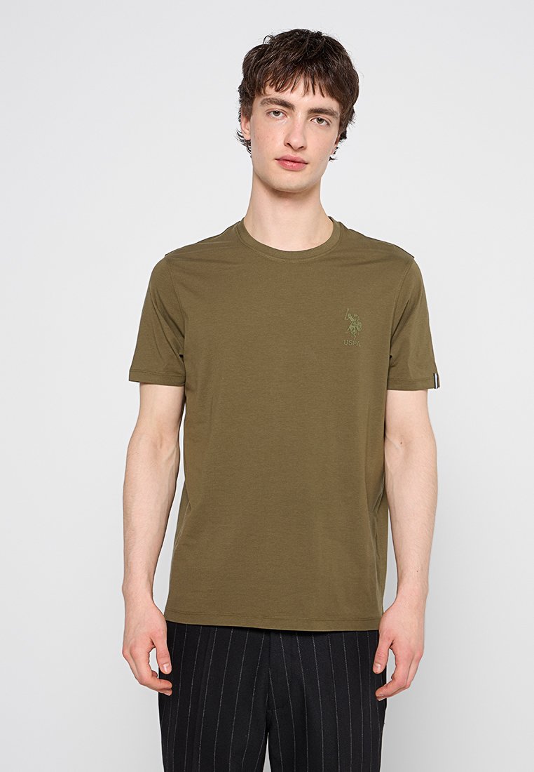 Olivenfarbendes Baumwoll-T-Shirt mit Rundhalsausschnitt und kurzen Ärmeln. Hat ein dezentes Logo auf der linken Brust und eine weiche Textur.
