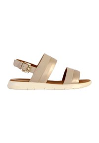 Sandalia de cuero beige con dos correas anchas y hebilla en el tobillo; suela plana de goma blanca con agarre texturizado. Diseño ligero y de punta abierta.