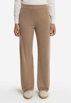 Beige vida byxor i mjuk, texturerad tyg. Midjan är elastisk och de är i kombination med ljusa sneakers.