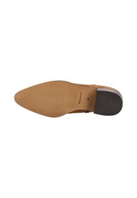 Braune Wildlederschuhe mit spitzem Zehenbereich, strukturiertem Gummisohle und dezentem Markendetail. Die Sohle ist glatt mit einem gerillten Muster für Halt.