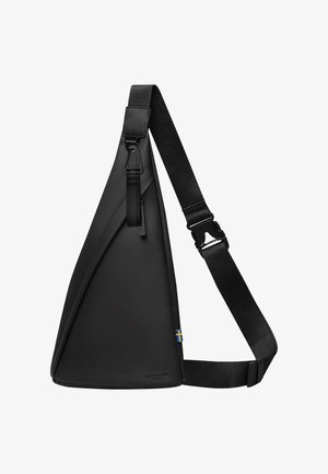 Borsa a tracolla nera realizzata in materiale liscio e resistente con un design angolato. Presenta una tracolla regolabile e dettagli in metallo, tra cui un logo e una bandiera.