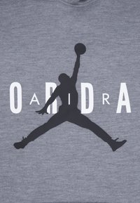 Sivkasta pulover s črno silhueto košarkarja v zraku, z besedo "OADIDRA" v bold belih črkah.