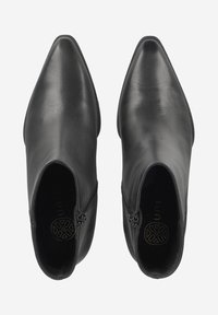 Bottines en cuir noir avec un bout pointu, fermeture éclair sur le côté et texture lisse. Logo intérieur visible, design minimaliste.