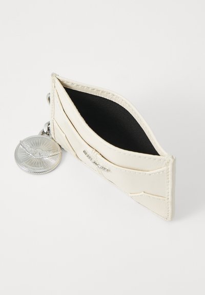 Portofel de carduri din piele de culoare crem, cu interior negru și accesorii din metal argintiu. Dispune de un compartiment pentru monede și mai multe sloturi pentru carduri.