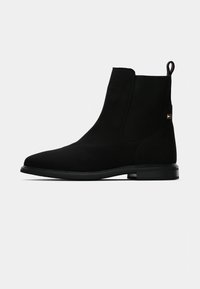 Stivale Chelsea nero in suede con lati in elastico, punta arrotondata e suola in gomma liscia. Dotato di una linguetta per una facile vestibilità.