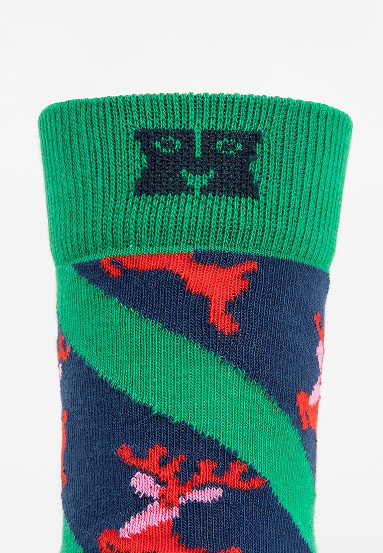 Kniestrumpf in Marineblau mit grünem geripptem Bündchen, das mit roten und rosa Rentiermustern sowie einem schwarzen Logo an der Oberseite versehen ist.