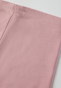 Lichtroze rekbare stof met een gladde textuur, zichtbare stiknaden bij de naden en geen kenmerkende patronen of hardwaredetails.