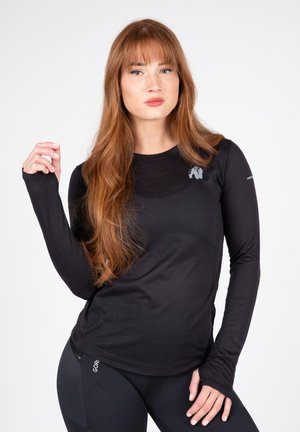 Sort langærmet træningsshirt med rund halsudskæring, der har et logo på brystet og tommelhuller i ærmerne for ekstra funktionalitet.