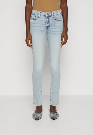 Jeans de mezclilla azul claro con un corte slim, diseño de cinco bolsillos y detalles de desgastado sutil. Combinados con zapatos planos gris de punta afilada.