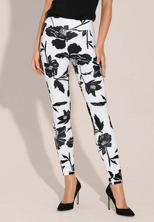 Zwart-witte bloemenleggings met een aangesloten ontwerp, met grote bloemenpatronen op een witte achtergrond en een gladde textuur.