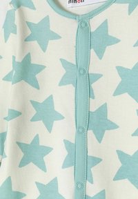 Bodie de manga larga en verde pálido con un patrón de estrellas azules más grandes, que cuenta con un cierre en la parte delantera de botones y un cuello acanalado.