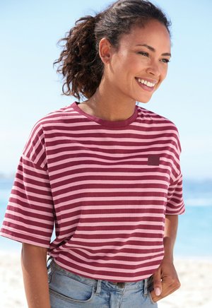 Maroon and pink striped short-sleeve t-shirt with a round neckline and a small brand logo tag. Worn with light denim shorts.