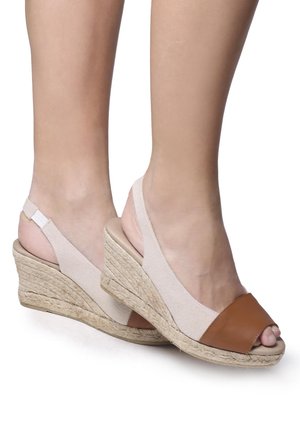 Wedge sandals with a beige elastic strap, brown leather toe cap, and woven jute platform. Open toe design with a slingback style.