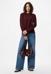 Bordo pleten pulover, ohlapen kroj, okrogla izreza; široke modre kavbojke; sijoča burdeos torba; bež gležnjarji s črnimi podplati.