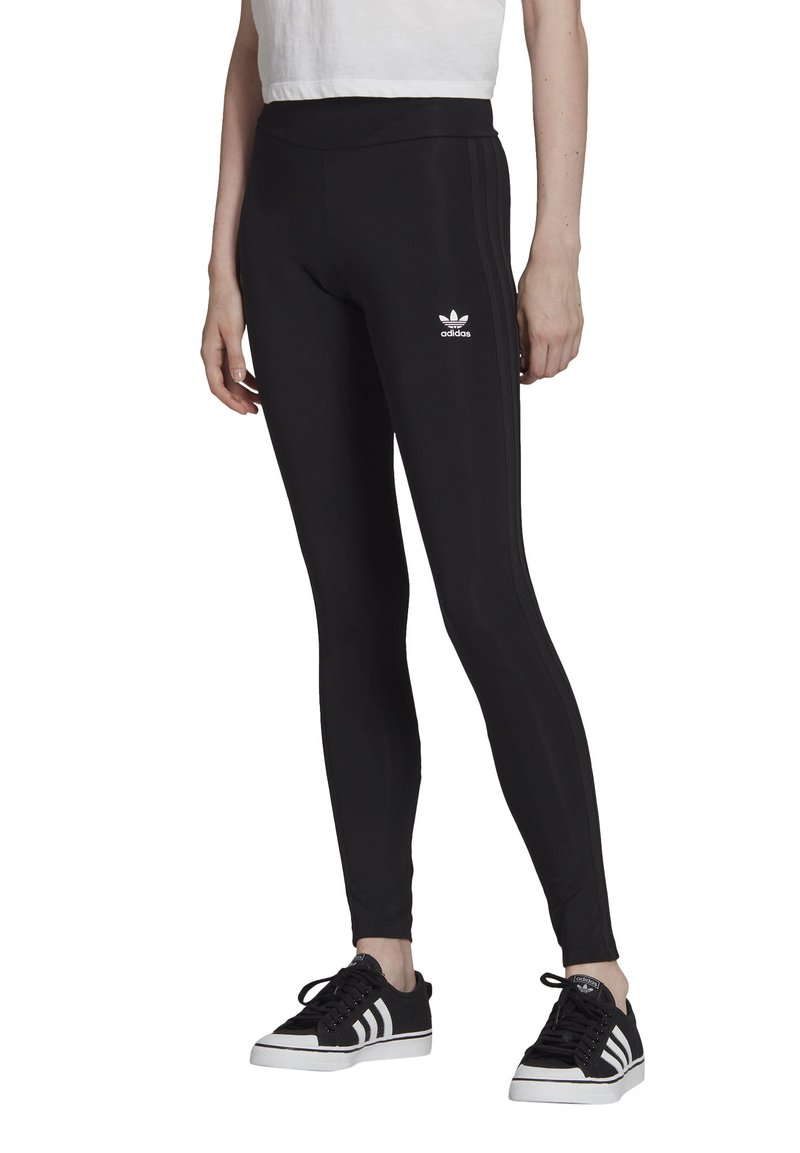 Melnas leggingas ar augstu jostasvietu, izgatavotas no elastīga materiāla. Iezīmes trīs baltas svītras gar malām un mazs balts logotips priekšā.