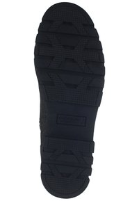 Semelle de chaussure en caoutchouc noir avec des motifs de grip texturés, présentant des rainures profondes et un talon renforcé pour la durabilité. Logo de la marque visible.