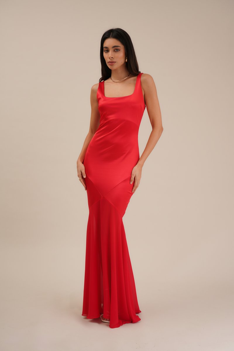 Robe de soirée en satin rouge avec un décolleté carré, un corsage ajusté et une jupe évasée, présentant des détails de coutures diagonales et une texture lisse.