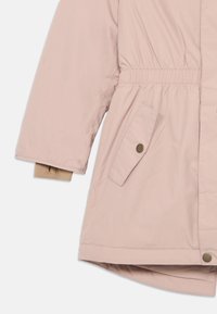 Giacca imbottita rosa chiaro con vita elastica, tasca laterale con bottone a pressione e polsini interni beige a contrasto. Tessuto elegante e liscio.