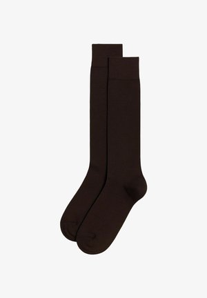 Chaussettes marron montantes en matériau lisse et extensible. Dotées d'un bord côtelé et d'un design de pointe sans couture pour le confort.
