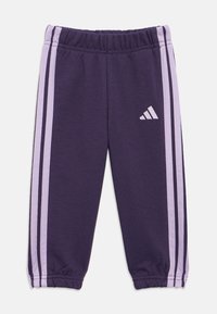 Pantaloni de jogging mov cu talie elastică, având dungi laterale de un mov deschis și un logo Adidas pe partea inferioară a piciorului. Textură moale a materialului.