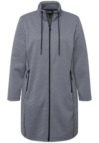 Cappotto lungo in un motivo geometrico, con colletto alto, zip frontale e tasche laterali. I colori includono blu navy e bianco.