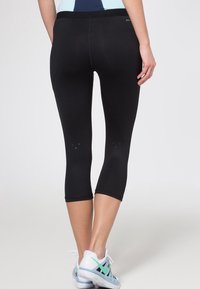 Schwarze Leggings mit cropped Schnitt, aus einem dehnbaren Material, mit glatter Textur und minimalen Designdetails.
