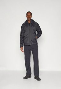 Sort lynlåsforsidejakke med hætte, lavet af letvægtsmateriale. Kombineret med matchende mørke bukser. Tekstureret overflade med glat finish.