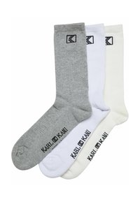 Tre par sokker i grå, hvid og off-white farver, lavet af strikmateriale, med sort logo og tekst ved kanten.