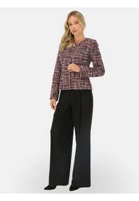 Fioletowa i wielokolorowa kurtka z tweedu z okrągłym dekoltem, zapinana na zamek, z długimi rękawami, zestawiona z czarnymi spodniami z szerokimi nogawkami i wysokim stanem.