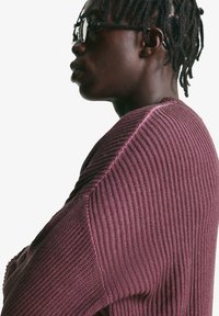 Purple ribbed knit sweater with a relaxed fit, featuring a textured design and subtle seam details, viewed from the side.