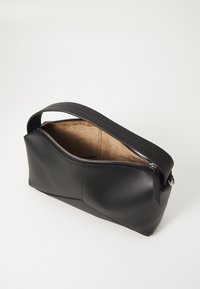 Sac en cuir noir avec fermeture éclair et une seule poignée. Dispose d'une texture lisse et d'un intérieur doublé de tissu clair.