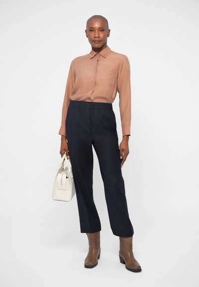 Brown long-sleeve button-up shirt, navy elastic-waist trousers, brown ankle boots, and a white handbag. Simple design, smooth texture.