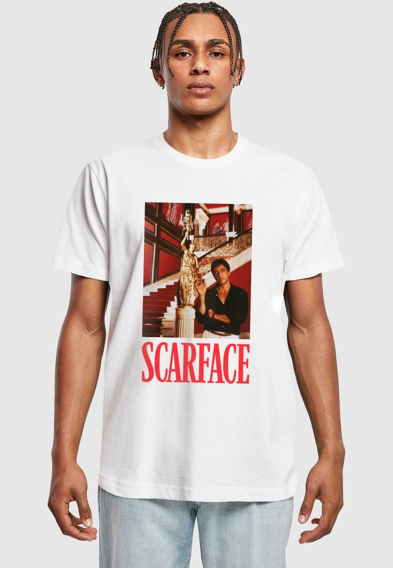 Hvid bomulds t-shirt med et stort print af en figur ved siden af en statue, med "SCARFACE" i fede røde bogstaver nederst.
