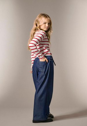 Maglietta a maniche lunghe a righe rosse e bianche abbinata a pantaloni larghi in denim scuro. I pantaloni presentano una vita elasticizzata e tasche.