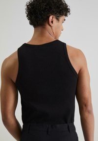 Schwarzes geripptes Tanktop mit breiten Schulterträgern und einem Rundhalsausschnitt, aus strukturiertem Stoff und in passgenauer Form.