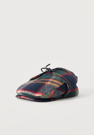 Καπέλο τύπου flat cap με πολύχρωμο καρό μοτίβο σε μπλε ναυτικό, πράσινο, κόκκινο και μπεζ, με μικρή μαύρη λεπτομέρεια κορδέλας στην κορυφή.
