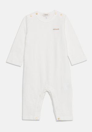 Grenouillère blanche à manches longues pour bébé avec des boutons dorés aux épaules et aux jambes, avec petit logo Versace doré sur la poitrine.