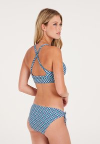 Blauwe patroon bikini set met een crisscross-straps ontwerp op de top, met verstelbare zijstrikjes op de broekjes. Smooth textuur.