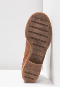 Brązowy skórzany but z teksturowaną gumową podeszwą, z płaskim obcasem i poziomymi rowkami dla lepszej przyczepności. Wytłoczone logo marki "TEN POINTS".