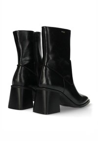 Černé kožené kotníkové boty s blokovým podpatkem, bočním zipem a hladkou texturou. Mají zaoblenou špičku a jemné švy.
